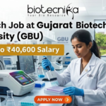 ₹40,600 Salary Research Job at Gujarat Biotechnology University (GBU) | JRF & SRF Openings ₹40,600 Salary Research Job at Gujarat Biotechnology University (GBU) JRF & SRF Openings. A focused female researcher in a white lab coat uses a multi-channel pipette on a microplate within a modern GBU laboratory. Large bold text reads: 'Research Job at Gujarat Biotechnology University (GBU)'. A yellow banner highlights 'Earn Upto ₹40,600 Salary'. The Biotecnika logo is at the top. The background features GBU lab equipment, a monitor with DNA graphs, another researcher, and GBU campus views. At the bottom center is an orange 'APPLY NOW' button with a right arrow.