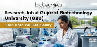 ₹40,600 Salary Research Job at Gujarat Biotechnology University (GBU) JRF & SRF Openings. A focused female researcher in a white lab coat uses a multi-channel pipette on a microplate within a modern GBU laboratory. Large bold text reads: 'Research Job at Gujarat Biotechnology University (GBU)'. A yellow banner highlights 'Earn Upto ₹40,600 Salary'. The Biotecnika logo is at the top. The background features GBU lab equipment, a monitor with DNA graphs, another researcher, and GBU campus views. At the bottom center is an orange 'APPLY NOW' button with a right arrow.