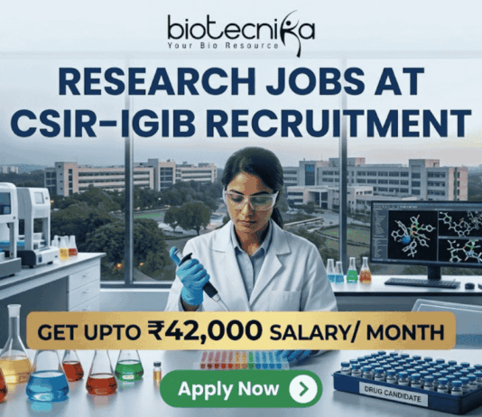 ₹42,000 Salary Research Jobs at Institute of Life Sciences | Apply Now ₹42,000 Salary Research Jobs at Institute of Life Sciences Apply Now. A job recruitment banner from Biotecnika for CSIR-IGIB. The headline reads 'RESEARCH JOBS AT CSIR-IGIB RECRUITMENT'. A female scientist in a lab coat uses a multi-channel pipette. The desk features beakers, a box of 'DRUG CANDIDATE' vials, and a monitor with a 3D molecular structure. A campus of buildings is visible through a large window. A gold banner highlights 'GET UPTO ₹42,000 SALARY/ MONTH'. An 'Apply Now' button is at the bottom.
