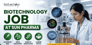 Biotechnology Job at Sun Pharma Opportunity for MSc & MTech Candidates. A professional promotional banner for a "Biotechnology Job at Sun Pharma." The top left displays the Biotecnika logo. The main header text boldly reads "BIOTECHNOLOGY JOB AT SUN PHARMA" in a green and dark color scheme. Below the title, four circular green icons are labeled: "ADVANCED R&D", "DRUG DISCOVERY", "GENETIC INNOVATION", and "CAREER PATHS". In the center, three floating circular graphics illustrate a DNA double helix, a colorful protein model, and a biochip. On the right side, a female researcher wearing a white lab coat and safety glasses works attentively with a laboratory bioreactor containing a golden liquid, set against a bright, modern pharmaceutical lab background. A prominent gold "APPLY NOW" button with an arrow sits at the bottom center-right.