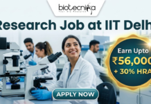 Research Job in Biomedical Engineering at IIT Delhi | Earn ₹56,000 per month Research Job in Biomedical Engineering at IIT Delhi | Earn ₹56,000 per month. Corporate-style job featured image banner (1280x720) for "Research Job at IIT Delhi" featuring the Biotecnika logo at the top center. The background shows a realistic, modern laboratory where a smiling young Indian female researcher in a white lab coat sits with a microscope, while two colleagues work behind her. On the right, a prominent gold and teal circular badge highlights text reading "Earn Upto ₹56,000 + 30% HRA". A sleek teal "APPLY NOW" button is positioned at the bottom center.